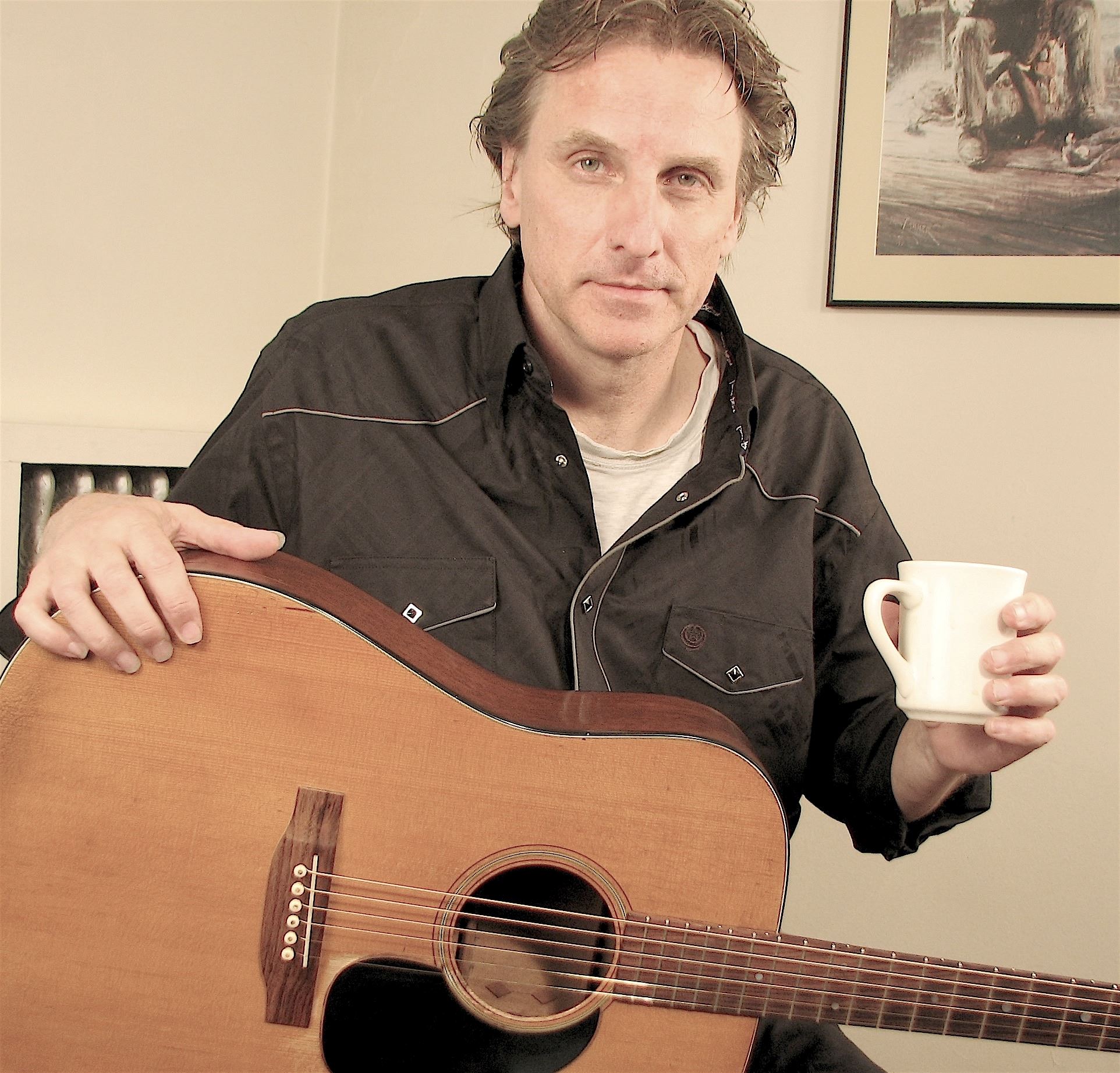 A photo of folk musician Mark Dvorak with his guitar.